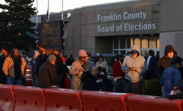 Voters wait outside of the Franklin County Board of Elections for the first day of in person early voting in Columbus, Ohio, Tuesday, Oct. 8, 2024. (AP Photo/Paul Vernon)