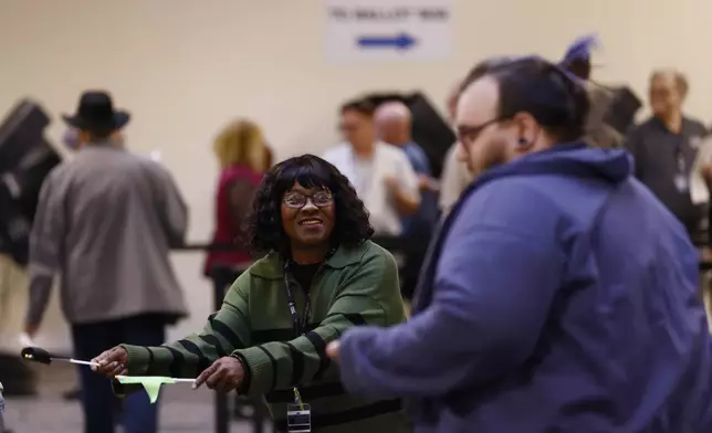 Poll worker Susan Henry directs voters to check in for the first day of in person early voting at the Franklin County Board of Elections in Columbus, Ohio, Tuesday, Oct. 8, 2024. (AP Photo/Paul Vernon)