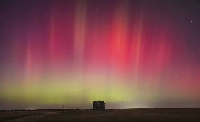 The northern lights are seen over a crumbling, abandoned farm house near Marquette, KS., Thursday, Oct. 10, 2024. (Travis Heying/The Wichita Eagle via AP)