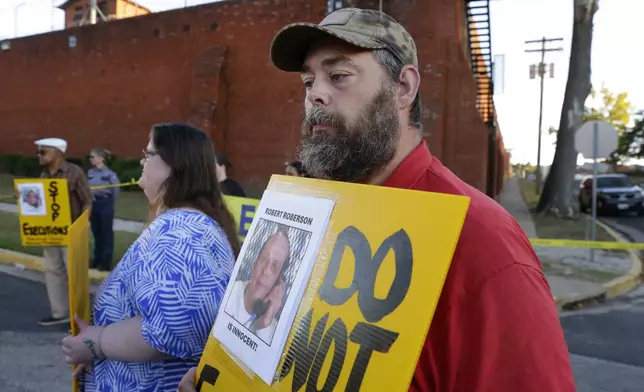 Thomas Roberson, right, older brother of condemned prisoner Robert Roberson, and Jennifer Martin, center left, holds signs with others as they protest outside the prison where Roberson is scheduled for execution at the Huntsville Unit of the Texas State Penitentiary Thursday, Oct. 17, 2024, in Huntsville, Texas. (AP Photo/Michael Wyke)