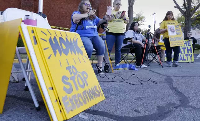 Dani Allen, center left with microphone, an anti-death penalty advocate, speaks during a protest outside the prison where Robert Roberson is scheduled for execution at the Huntsville Unit of the Texas State Penitentiary, Thursday, Oct. 17, 2024, in Huntsville, Texas. (AP Photo/Michael Wyke)