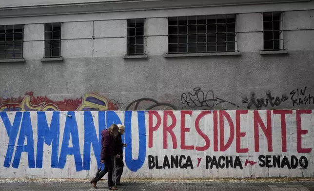 Pedestrians walk past a campaign mural promoting Frente Amplio presidential candidate Yamandu Orsi, ahead of Sunday's upcoming general election, in Montevideo, Uruguay, Friday, Oct. 25, 2024. (AP Photo/Natacha Pisarenko)