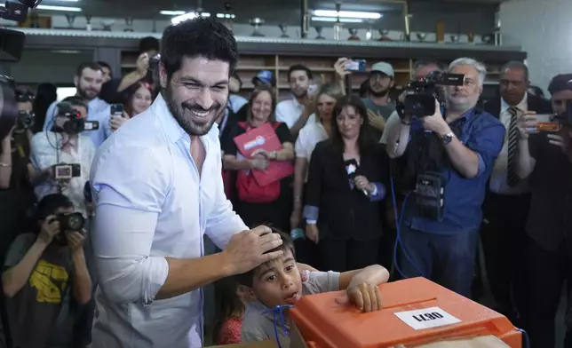 Andres Ojeda, Colorado Party presidential candidate, smiles after voting alongside his nephew at a polling station during general elections in Montevideo, Uruguay, Sunday, Oct. 27, 2024. (AP Photo/Matilde Campodonico)