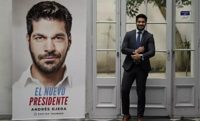 Andres Ojeda, Colorado Party presidential candidate, poses for a photo alongside one of his campaign banners, ahead of Sunday's upcoming general election, in Montevideo, Uruguay, Friday, Oct. 25, 2024. (AP Photo/Natacha Pisarenko)