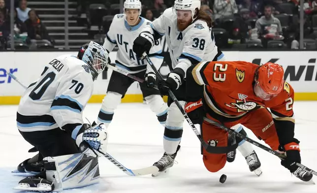 Anaheim Ducks center Mason McTavish, right, and Utah Hockey Club center Liam O'Brien, second from right, battle for the puck in front on goaltender Karel Vejmelka, left, during the first period of an NHL preseason hockey game, Wednesday, Oct. 2, 2024, in Anaheim, Calif. (AP Photo/Mark J. Terrill)