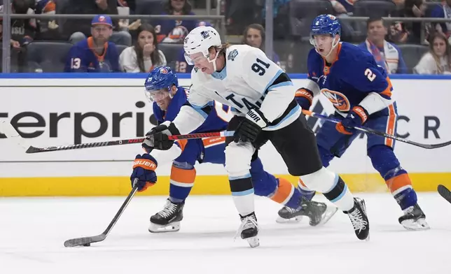 New York Islanders' Brock Nelson (29) fights for control of the puck with Utah Hockey Club's Josh Doan (91) during the first period of an NHL hockey game Thursday, Oct. 10, 2024, in Elmont, N.Y. (AP Photo/Frank Franklin II)