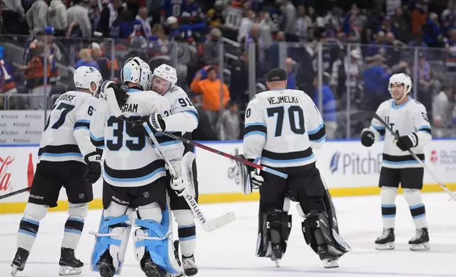 Utah Hockey Club's Josh Doan (91) hugs goaltender Connor Ingram (39) as they celebrate with teammates after an NHL hockey game against the New York Islanders Thursday, Oct. 10, 2024, in Elmont, N.Y. (AP Photo/Frank Franklin II)