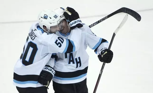 Utah Hockey Club's Sean Durzi, left, and Clayton Keller, right, react after Keller scored the winning goal during overtime of an NHL hockey game against the New York Rangers, Saturday, Oct. 12, 2024, in New York. (AP Photo/Pamela Smith)