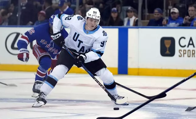 Utah Hockey Club's Logan Cooley (92) skates with the puck during the second period of an NHL hockey game against the New York Rangers, Saturday, Oct. 12, 2024, in New York. (AP Photo/Pamela Smith)