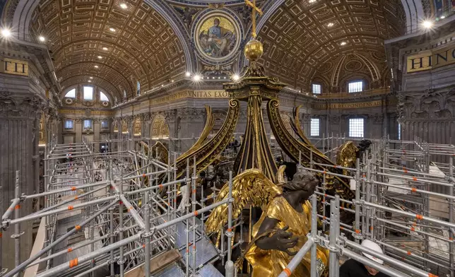 Experts show to journalists, Tuesday, Oct. 8, 2024, the restoration works of Bernini's monumental bronze canopy, situated beneath Michelangelo's massive dome and towering 95 feet above the papal altar that sits directly above the Tomb of Saint Peter inside St. Peter's Basilica at The Vatican, where the gleaming bronze of its twisting Solomonic columns has been concealed by scaffolds for nine months while expert conservators worked meticulously on its intricate surface. (AP Photo/Domenico Stinellis)