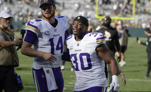 Minnesota Vikings quarterback Sam Darnold (14) and fullback C.J. Ham (30) celebrate the team's win against the Green Bay Packers after an NFL football game Sunday, Sept. 29, 2024, in Green Bay, Wis. (AP Photo/Matt Ludtke)