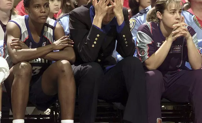 FILE - New York Liberty players from left, Crystal Robinson, Rebecca Lobo, who is injured, and Becky Hammon sit on the bench as the Liberty fall behind during the first half against the Houston Comets in Game 2 of the WNBA Finals, Sept. 4, 1999, in Houston. (AP Photo/David J. Phillip, File)