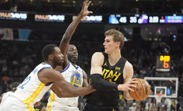 Golden State Warriors forwards Andrew Wiggins, left, and Draymond Green (23) defend against Utah Jazz forward Lauri Markkanen, right, in the first half of an NBA basketball game Friday, Oct. 25, 2024, in Salt Lake City. (AP Photo/George Frey)