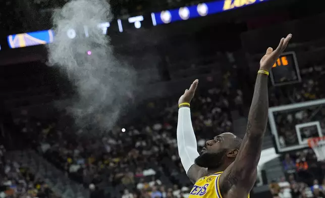 Los Angeles Lakers forward LeBron James (23) tosses chalk into the air before a NBA preseason basketball against the Golden State Warriors, Tuesday, Oct. 15, 2024, in Las Vegas. (AP Photo/John Locher)