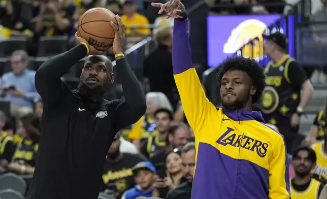 Los Angeles Lakers forward LeBron James, left, and guard Bronny James warm up before a NBA preseason basketball game against the Golden State Warriors, Tuesday, Oct. 15, 2024, in Las Vegas. (AP Photo/John Locher)