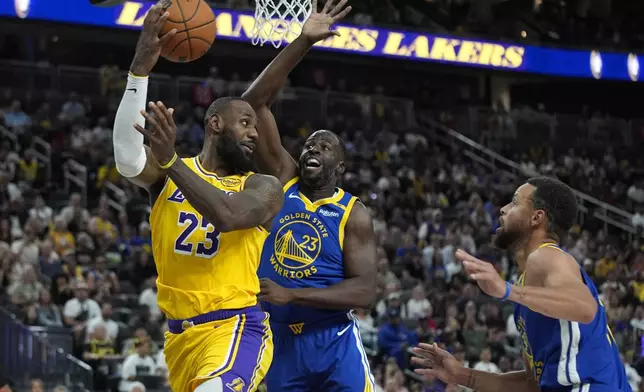 Los Angeles Lakers forward LeBron James, left, passes around Golden State Warriors forward Draymond Green during the first half of a NBA preseason basketball game Tuesday, Oct. 15, 2024, in Las Vegas. (AP Photo/John Locher)