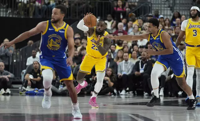 Los Angeles Lakers forward LeBron James (23) grabs the ball against Golden State Warriors forward Trayce Jackson-Davis (32) during the first half of a NBA preseason basketball game Tuesday, Oct. 15, 2024, in Las Vegas. (AP Photo/John Locher)