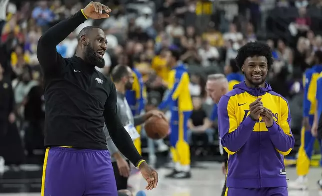 Los Angeles Lakers forward LeBron James, left, and guard Bronny James warm up before a NBA preseason basketball game against the Golden State Warriors, Tuesday, Oct. 15, 2024, in Las Vegas. (AP Photo/John Locher)