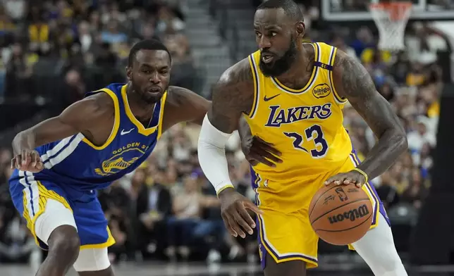 Los Angeles Lakers forward LeBron James (23) drives against Golden State Warriors forward Andrew Wiggins (22) during the first half of a NBA preseason basketball game Tuesday, Oct. 15, 2024, in Las Vegas. (AP Photo/John Locher)