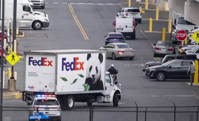 Police vehicles escort a FedEx truck carrying giant pandas to the National Zoo after they arrived at Dulles International Airport from China on Tuesday, Oct. 15, 2024 in Sterling, Va. (AP Photo/Kevin Wolf)