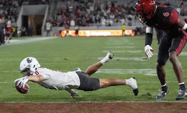 Washington State wide receiver Carlos Hernandez leaps into the end zone as San Diego State safety Eric Butler looks on during the second half of an NCAA college football game Saturday, Oct. 26, 2024, in San Diego. (AP Photo/Gregory Bull)