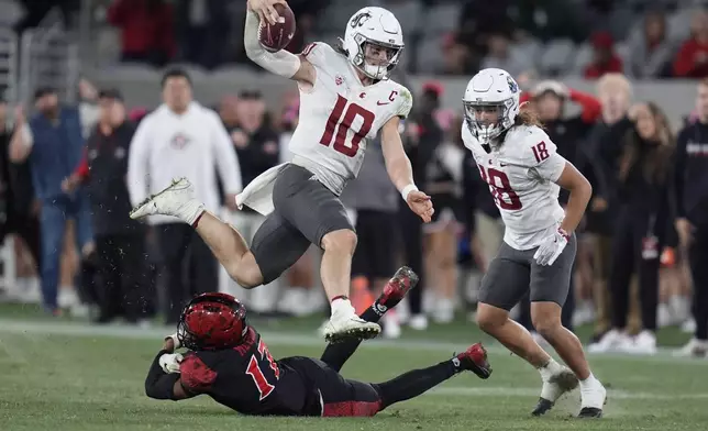 Washington State quarterback John Mateer, above, leaps over San Diego State safety Deshawn McCuin during the second half of an NCAA college football game Saturday, Oct. 26, 2024, in San Diego. (AP Photo/Gregory Bull)