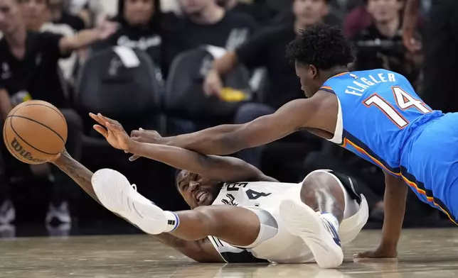 San Antonio Spurs guard Blake Wesley, left, and Oklahoma City Thunder forward Adam Flagler, right, scramble for a loose ball during the second half of a preseason NBA basketball game in San Antonio, Monday, Oct. 7, 2024. (AP Photo/Eric Gay)