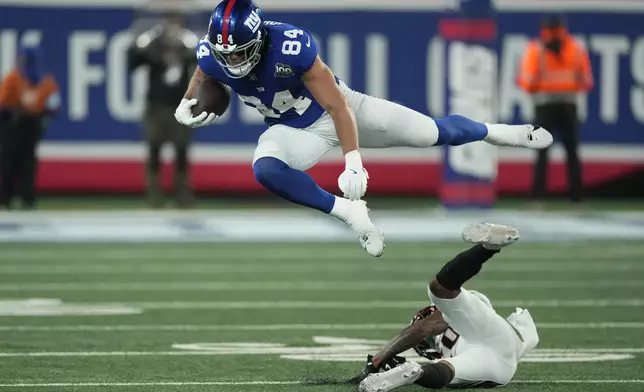 New York Giants tight end Theo Johnson (84) leaps over a Cincinnati Bengals defender during the second half of an NFL football game, Sunday, Oct. 13, 2024, in East Rutherford, N.J. (AP Photo/Seth Wenig)