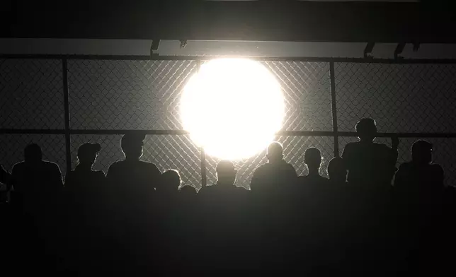 Fans watch of Game 1 of a baseball NL Division Series between the Philadelphia Phillies and the New York Mets as the sun sets, Saturday, Oct. 5, 2024, in Philadelphia. (AP Photo/Matt Slocum)