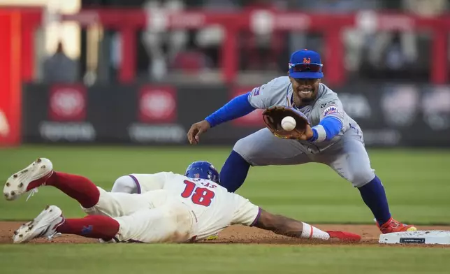 Philadelphia Phillies' Johan Rojas (18) dives safely back to second as New York Mets shortstop Francisco Lindor tries to tag him for a pickoff during the fifth inning of Game 1 of a baseball NL Division Series, Saturday, Oct. 5, 2024, in Philadelphia. (AP Photo/Chris Szagola)