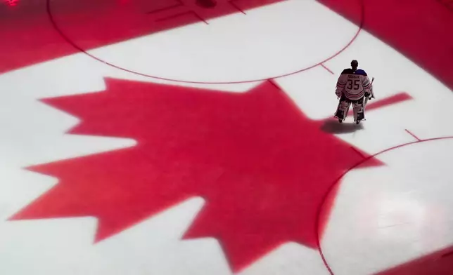 Edmonton Oilers goaltender Olivier Rodrigue stands on the ice as the flag of Canada is projected during the Canadian national anthem before a preseason NHL hockey game against the Seattle Kraken, Wednesday, Oct. 2, 2024, in Seattle. (AP Photo/Lindsey Wasson)