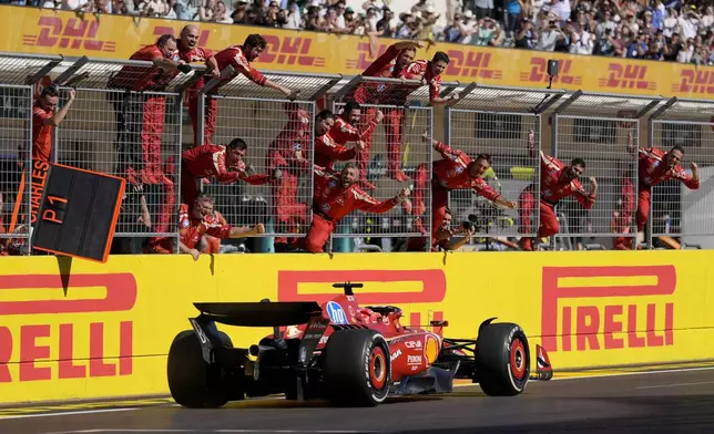 Team members stand along the fence celebrating as Ferrari driver Charles Leclerc, of Monaco, wins the U.S. Grand Prix auto race at Circuit of the Americas, Sunday, Oct. 20, 2024, in Austin, Texas. (AP Photo/Eric Gay)