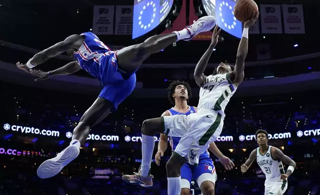 Milwaukee Bucks' AJ Johnson, right, goes up for a shot against Philadelphia 76ers' Jared McCain, center, and Adem Bona during the second half of an NBA basketball game, Wednesday, Oct. 23, 2024, in Philadelphia. (AP Photo/Matt Slocum)