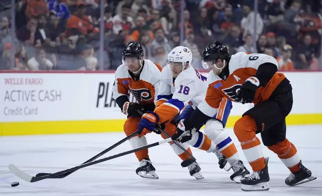 New York Islanders' Pierre Engvall, center, battles for the puck against Philadelphia Flyers' Cam York, left, and Travis Sanheim during the first period of a preseason NHL hockey game, Thursday, Sept. 26, 2024, in Philadelphia. (AP Photo/Matt Slocum)