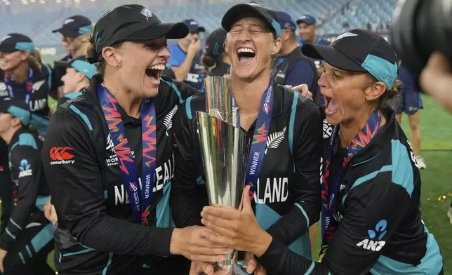 New Zealand's captain Sophie Devine, center, poses with teammates Lea Tahuhu, left, and Suzie Bates with the trophy after winning the ICC Women's T20 World Cup 2024 final match against South Africa at Dubai International Cricket Stadium, United Arab Emirates, Sunday, Oct. 20, 2024. (AP Photo/Altaf Qadri)