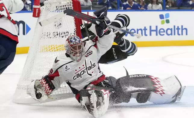 Washington Capitals goaltender Charlie Lindgren (79) makes a save as he gets knocked over by Tampa Bay Lightning center Luke Glendening during the second period of an NHL hockey game Saturday, Oct. 26, 2024, in Tampa, Fla. (AP Photo/Chris O'Meara)