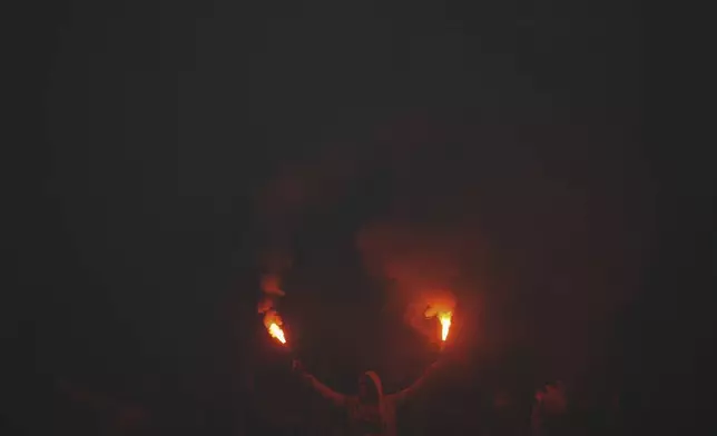 A Uruguay Penarol fan holds flares prior to a Copa Libertadores soccer match against Brazil's Flamengo at Campeon del Siglo Stadium in Montevideo, Uruguay, Thursday, Sept. 26, 2024. (AP Photo/Matilde Campodonico)