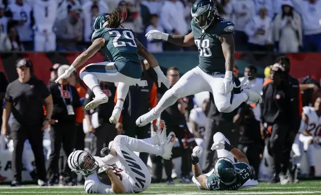 Philadelphia Eagles cornerback Avonte Maddox (29) and defensive tackle Jalen Carter (98) try to avoid contact with downed Cincinnati Bengals tight end Mike Gesicki, bottom left, and Eagles' Zack Baun (53) during the first half of an NFL football game, Sunday, Oct. 27, 2024 in Cincinnati. (AP Photo/Carolyn Kaster)