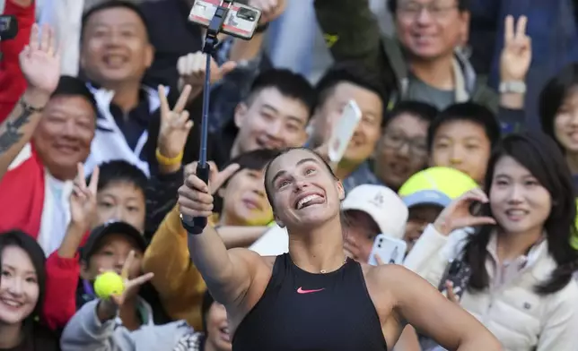 Aryna Sabalenka of Belarus takes a selfie with fans after winning against Madison Keys of the United States during their women's singles match of the China Open tennis tournament, at the National Tennis Center in Beijing, Wednesday, Oct. 2, 2024. (AP Photo/Achmad Ibrahim)