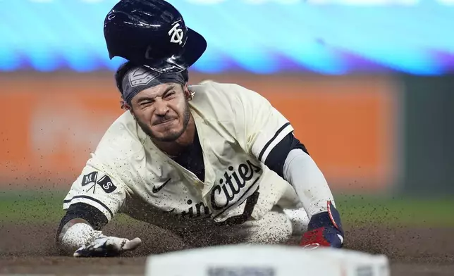 Minnesota Twins' Austin Martin slides into third base after a single hit by teammate Carlos Correa during the third inning of a baseball game against the Miami Marlins, Thursday, Sept. 26, 2024, in Minneapolis. (AP Photo/Abbie Parr)