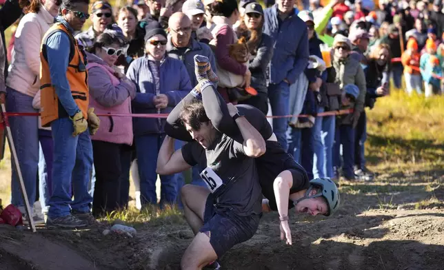 Nic Vinsonhaler looses his footing while carrying Tara Rogowski during the North American Wife Carrying Championship, Saturday, Oct. 12, 2024, at Sunday River ski resort in Newry, Maine. (AP Photo/Robert F. Bukaty)