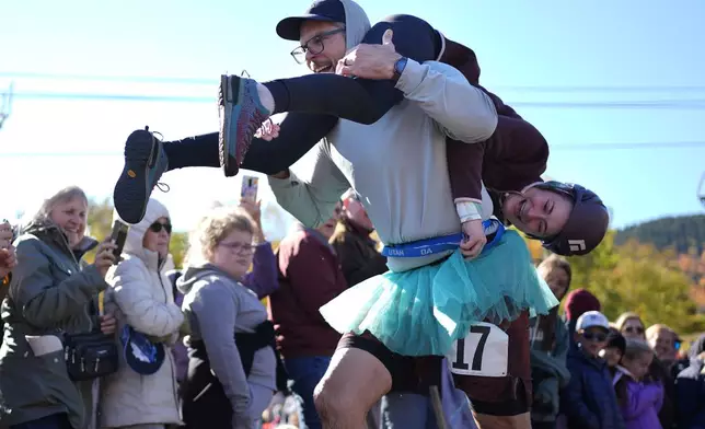 Galen Staats carries Amy Bannon during the North American Wife Carrying Championship, Saturday, Oct. 12, 2024, at Sunday River ski resort in Newry, Maine. (AP Photo/Robert F. Bukaty)