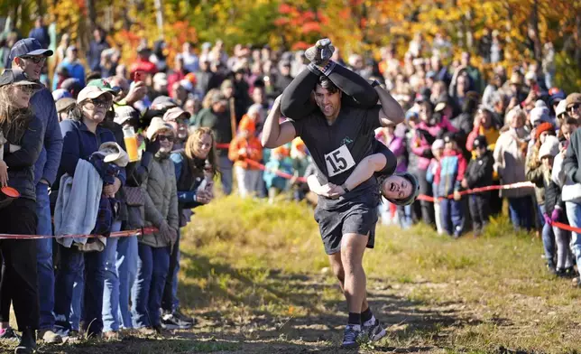 Nic Vinsonhaler carries Tara Rogowski while competing in the North American Wife Carrying Championship, Saturday, Oct. 12, 2024, at Sunday River ski resort in Newry, Maine. (AP Photo/Robert F. Bukaty)