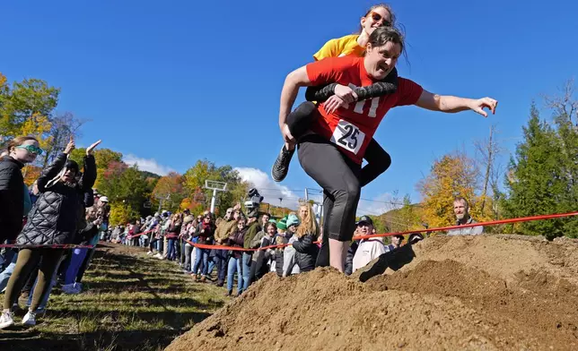 Molly Sunburn carries Megan Crowley over a sand pile during the North American Wife Carrying Championship, Saturday, Oct. 12, 2024, at Sunday River ski resort in Newry, Maine. (AP Photo/Robert F. Bukaty)