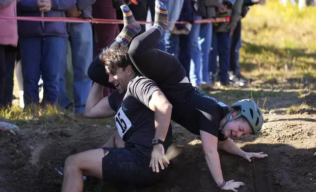 Nic Vinsonhaler looses his footing while carrying Tara Rogowski during the North American Wife Carrying Championship, Saturday, Oct. 12, 2024, at Sunday River ski resort in Newry, Maine. (AP Photo/Robert F. Bukaty)