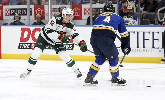 Minnesota Wild's Matt Boldy (12) passes the puck while St. Louis Blues' Nick Leddy (4) defends during the first period of an NHL hockey game Tuesday, Oct. 15, 2024, in St. Louis. (AP Photo/Scott Kane)