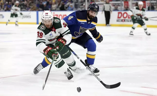 Minnesota Wild's Ryan Hartman (38) and St. Louis Blues' Nick Leddy (4) vie for control of the puck during the first period of an NHL hockey game Tuesday, Oct. 15, 2024, in St. Louis. (AP Photo/Scott Kane)