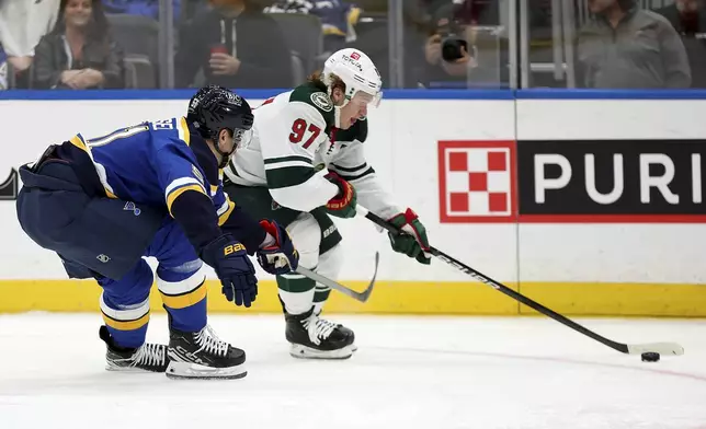 Minnesota Wild's Kirill Kaprizov (97) controls the puck while under pressure from St. Louis Blues' Matthew Kessel (51) during the first period of an NHL hockey game Tuesday, Oct. 15, 2024, in St. Louis. (AP Photo/Scott Kane)