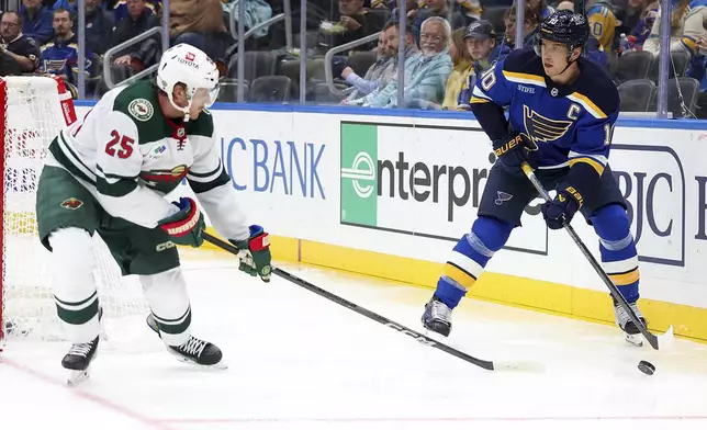 St. Louis Blues' Brayden Schenn (10) handles the puck as Minnesota Wild's Jonas Brodin (25) defends during the second period of an NHL hockey game Tuesday, October 15, 2024, in St. Louis. (AP Photo/Scott Kane)