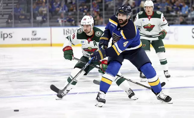 St. Louis Blues' Nick Leddy (4) passes the puck while under pressure from Minnesota Wild's Mats Zuccarello (36) during the second period of an NHL hockey game Tuesday, October 15, 2024, in St. Louis. (AP Photo/Scott Kane)